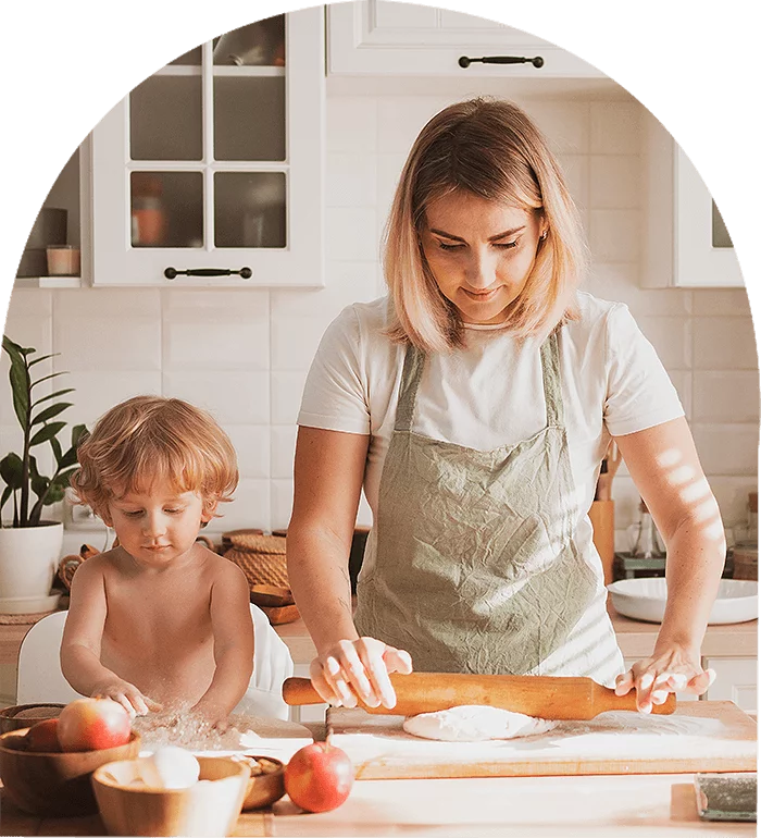 A woman and child kneading dough in a kitchen, bonding over baking